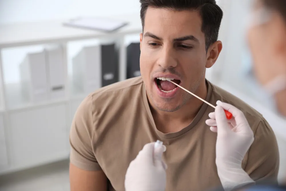 Doctor taking sample for DNA test from man in clinic Doctor taking sample for DNA test from man in clinic